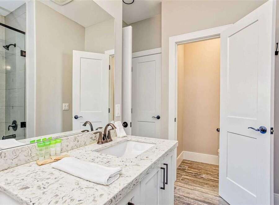 This modern bathroom features a sleek vanity with a quartz countertop and a undermount sink, complemented by a bronze faucet.
