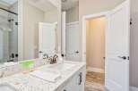 This modern bathroom features a sleek vanity with a quartz countertop and a undermount sink, complemented by a bronze faucet.