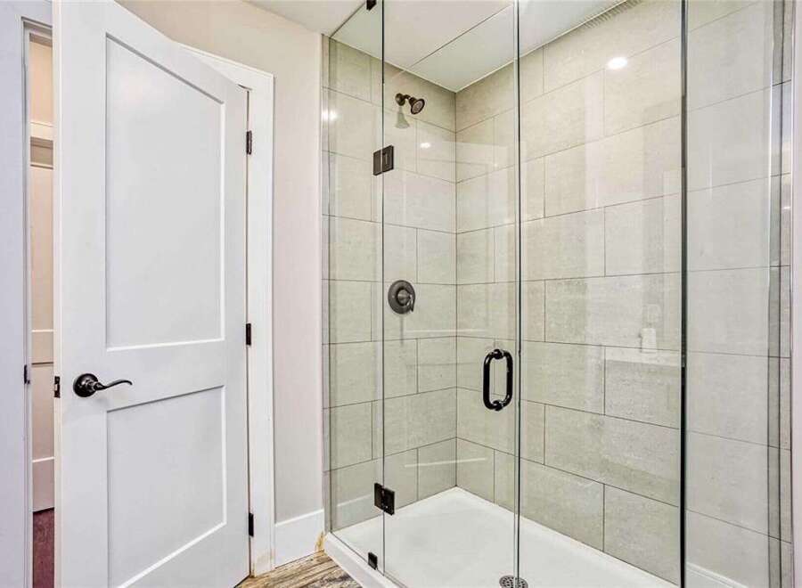 Step into this modern bathroom featuring a sleek glass-enclosed shower with elegant tilework and a rainfall showerhead.