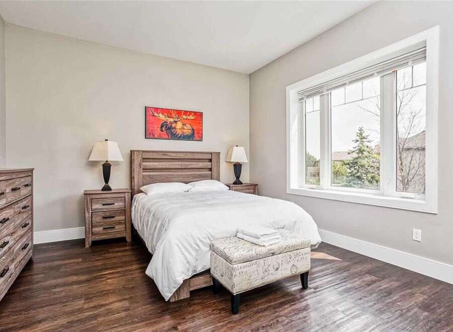 This charming bedroom features a rustic wooden bed frame and matching nightstands, complemented by a large window offering scenic views.