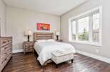 This charming bedroom features a rustic wooden bed frame and matching nightstands, complemented by a large window offering scenic views.