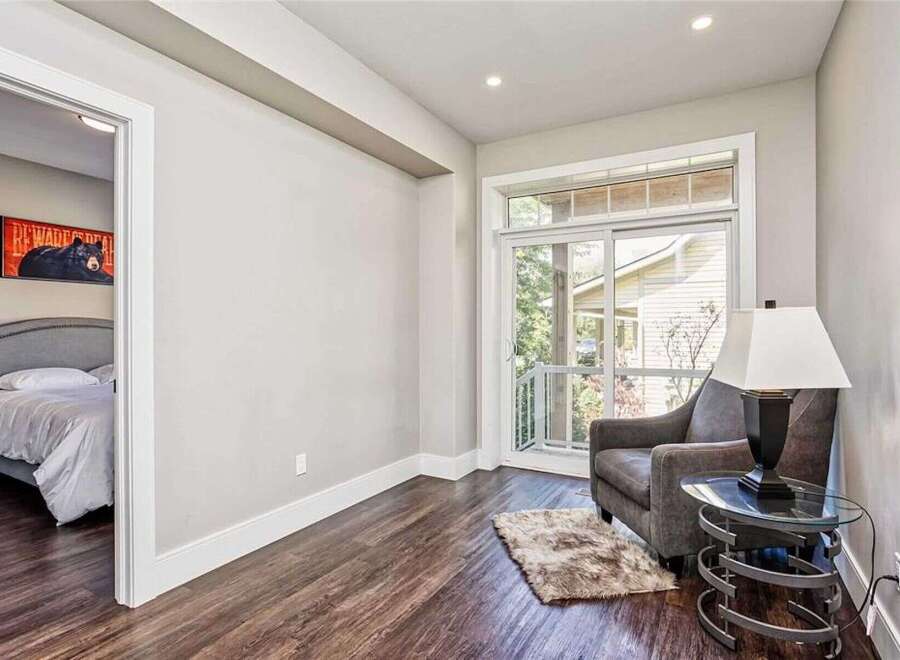 Step into this inviting space featuring a cozy bedroom with a striking bear-themed artwork and a comfortable armchair by a large sliding glass door.