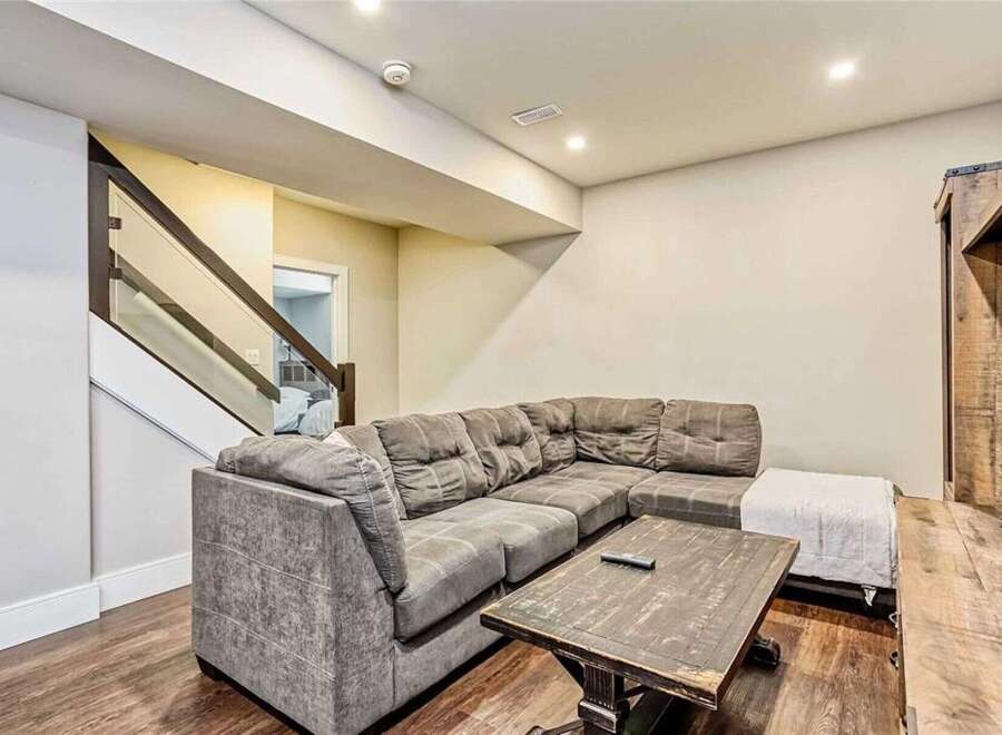 This modern living space features a spacious sectional sofa perfect for family gatherings, complemented by a rustic coffee table and a white ottoman.