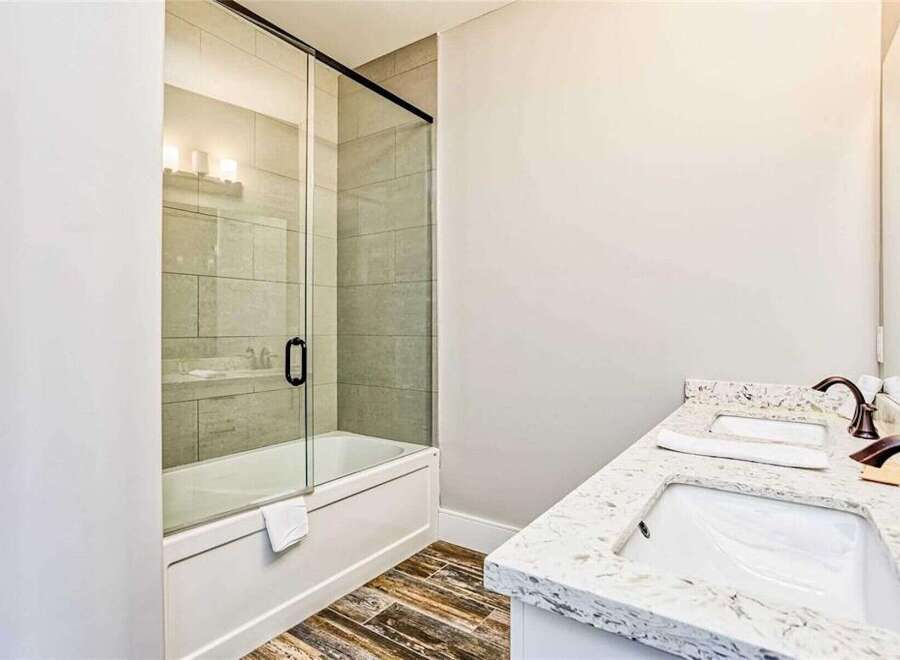 Experience modern luxury in this stunning bathroom featuring a sleek glass-enclosed bathtub and shower.