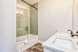 Experience modern luxury in this stunning bathroom featuring a sleek glass-enclosed bathtub and shower.