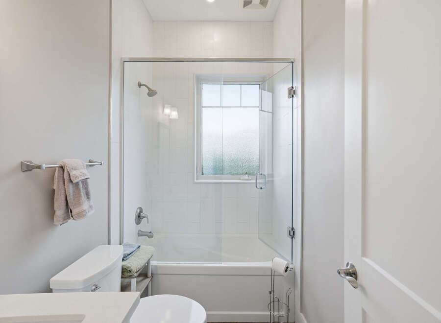 This modern bathroom features a sleek glass-enclosed shower and tub combination, perfect for a relaxing soak.