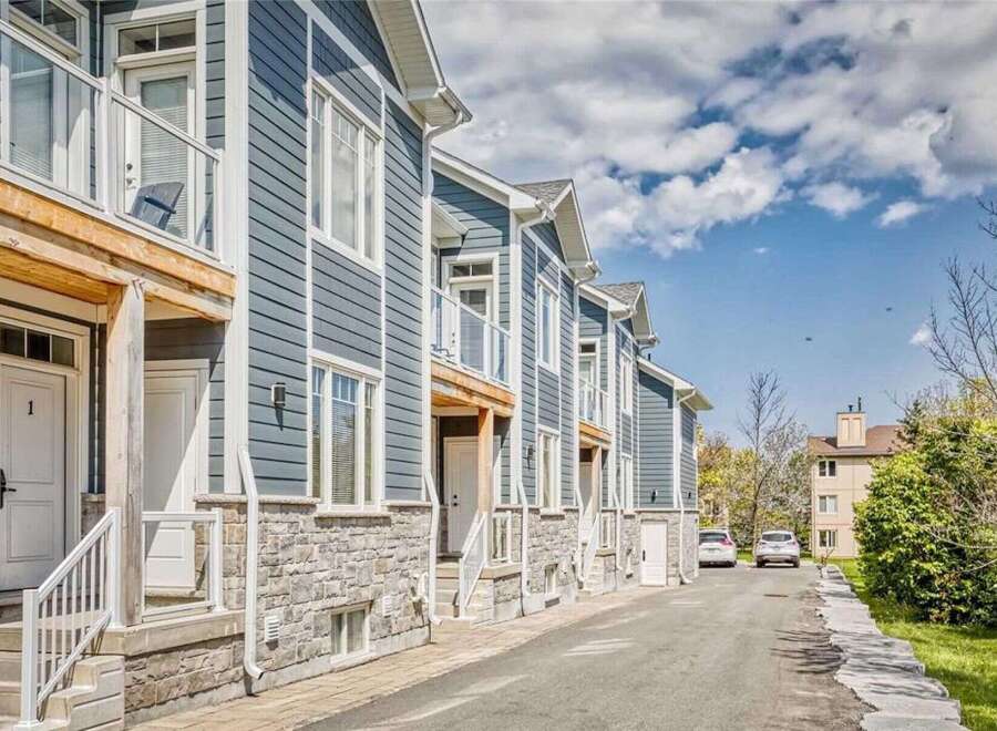 Discover modern living in this stunning townhouse complex, featuring elegant blue siding and charming stone accents.