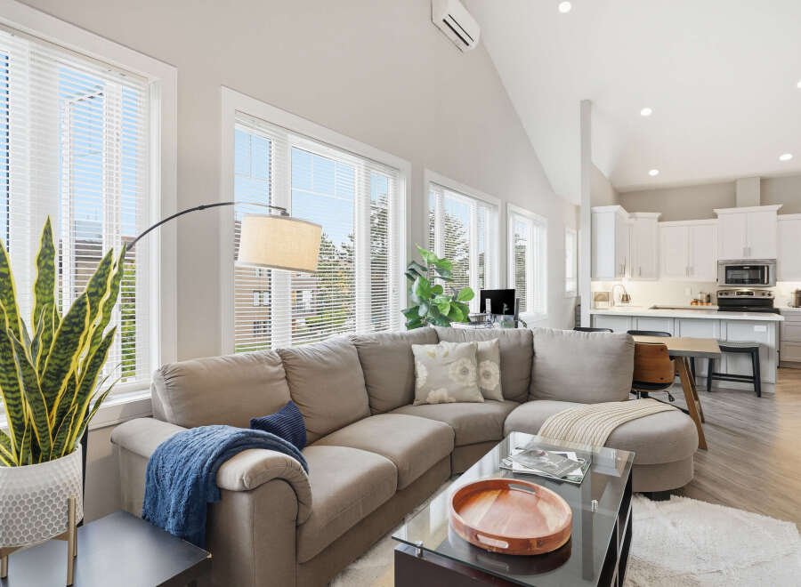 Experience modern living in this spacious open-concept home, featuring a comfortable sectional sofa and a sleek, contemporary kitchen.