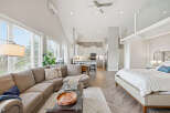 Experience modern living in this open-concept studio featuring a spacious sectional sofa, a sleek kitchen with ample cabinetry, and a comfortable king-sized bed.