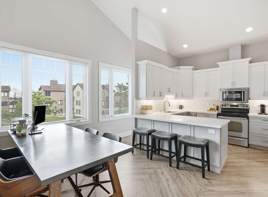 Experience modern living in this stunning open-concept kitchen and dining area, featuring vaulted ceilings and abundant natural light from large windows.