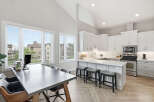Experience modern living in this stunning open-concept kitchen and dining area, featuring vaulted ceilings and abundant natural light from large windows.