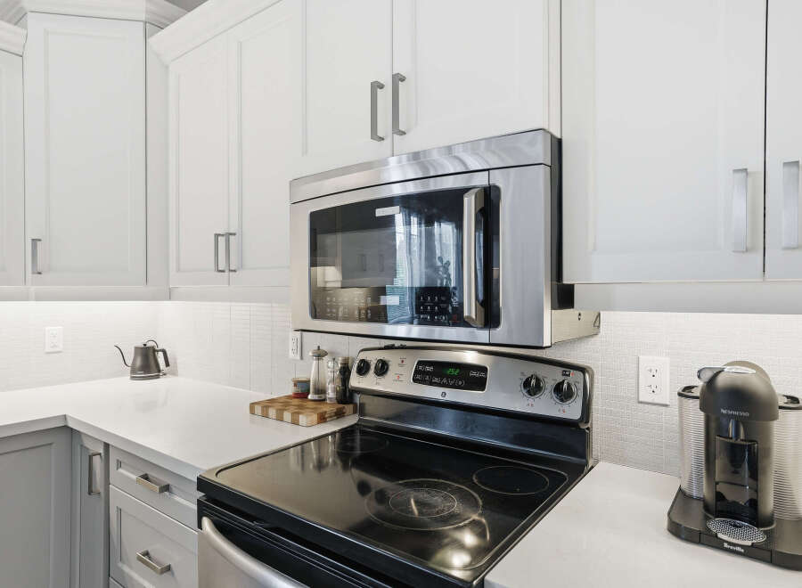 Experience modern convenience in this sleek kitchen, featuring a stainless steel microwave oven mounted above a smooth-top electric range.