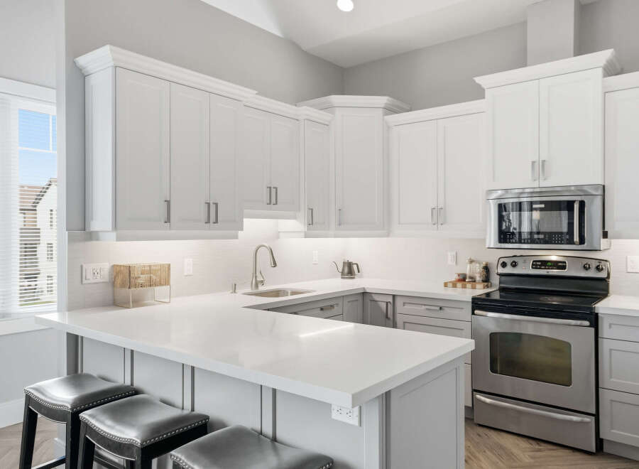 Experience modern living in this stunning kitchen featuring sleek white cabinetry and a spacious quartz countertop island perfect for entertaining.