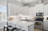 Experience modern living in this stunning kitchen featuring sleek white cabinetry and a spacious quartz countertop island perfect for entertaining.