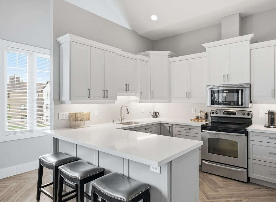 Experience modern living in this stunning kitchen featuring sleek white cabinetry and a spacious quartz countertop island perfect for entertaining.