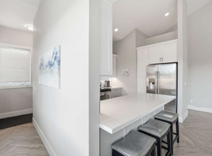 Experience modern living in this stunning kitchen featuring a sleek white quartz island with bar seating, perfect for casual dining and entertaining.