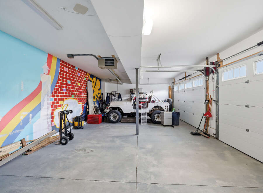 This spacious garage offers ample room for vehicles and storage, featuring a unique mural on one wall.