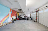 This spacious garage offers ample room for vehicles and storage, featuring a unique mural on one wall.
