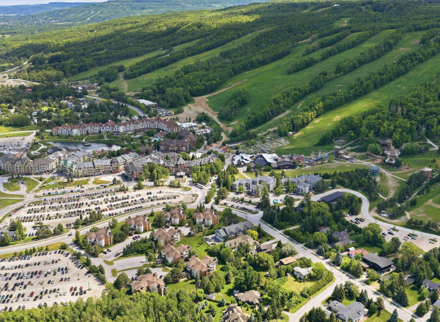 Discover this stunning aerial view of a vibrant mountain resort community, showcasing a blend of residential properties and recreational facilities.