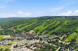 Experience the ultimate mountain lifestyle with this stunning aerial view of a vibrant ski resort village nestled against lush green hills.