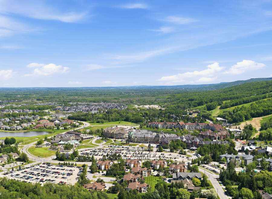 Discover this stunning aerial view of a vibrant mountain resort community, showcasing a mix of charming residential homes and a bustling village center.