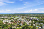 Discover this stunning aerial view of a picturesque resort community, showcasing a harmonious blend of residential buildings, lush green spaces, and a serene lake.