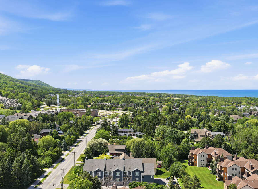 Discover this stunning aerial view showcasing a vibrant community nestled amidst lush greenery and rolling hills.