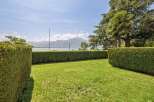 Enjoy breathtaking lake and mountain views from this stunning property, framed by meticulously manicured hedges and lush green lawns.