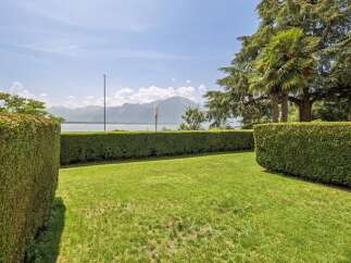 Enjoy breathtaking lake and mountain views from this stunning property, framed by meticulously manicured hedges and lush green lawns.