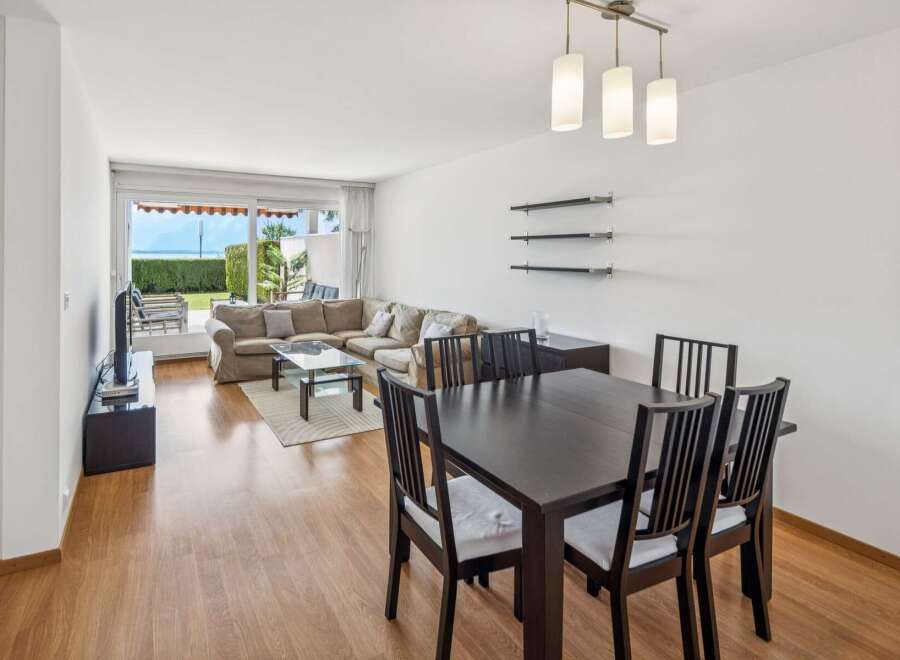 Experience coastal living in this spacious living and dining area, featuring a large sectional sofa and a modern dining set.