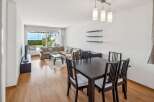 Experience coastal living in this spacious living and dining area, featuring a large sectional sofa and a modern dining set.