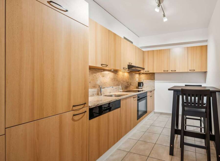 This modern kitchen features sleek, light wood cabinetry offering ample storage space.