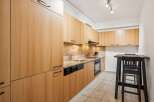 This modern kitchen features sleek, light wood cabinetry offering ample storage space.