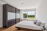 Experience modern living in this serene bedroom featuring a spacious dark wood wardrobe with frosted glass panels.