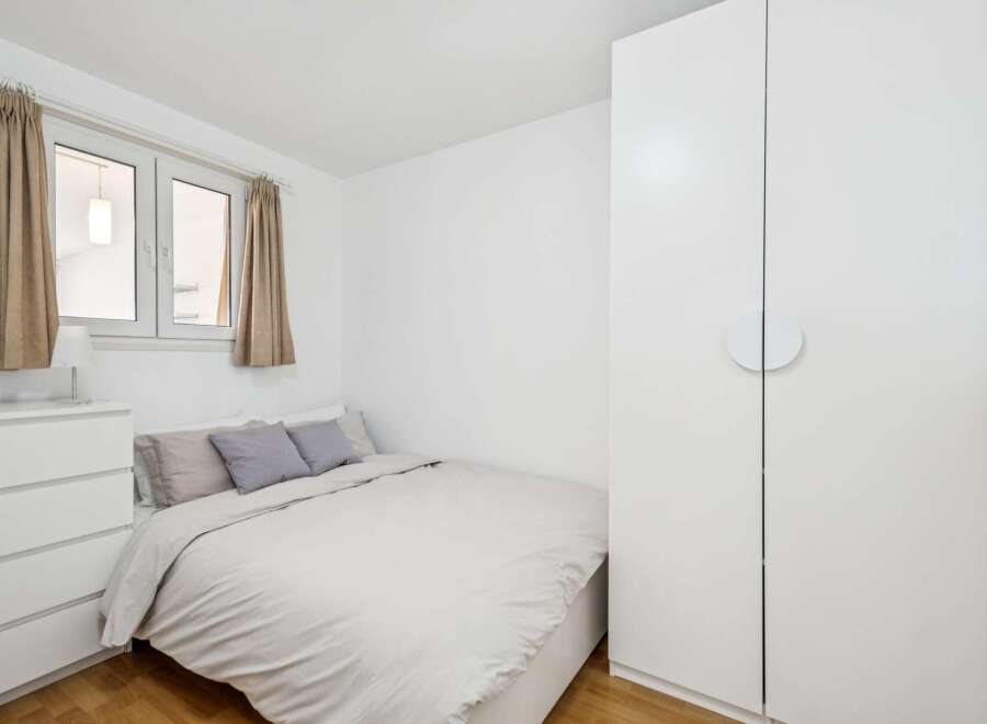 Discover this cozy bedroom featuring a comfortable bed with neutral bedding and accent pillows.