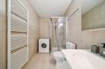 This modern bathroom features a convenient washing machine, a sleek shower enclosure, and a comfortable toilet.