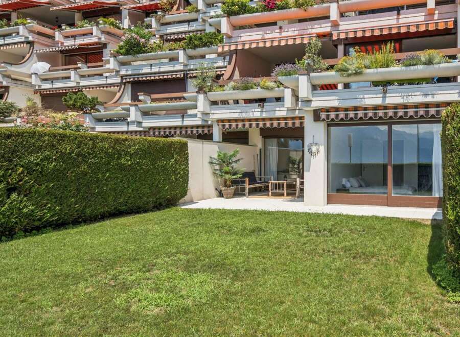 Experience luxurious living with this stunning property featuring multiple balconies adorned with lush greenery and vibrant flowers.