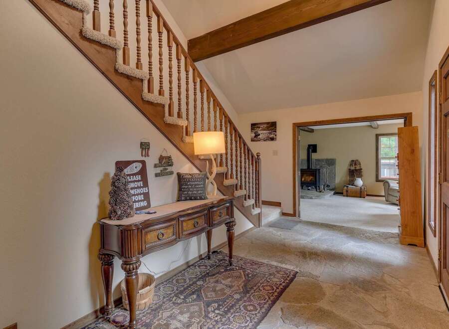 Step into a warm and inviting entryway featuring a rustic wooden console table adorned with charming cabin-themed decor.