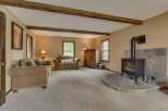 Cozy living room featuring a stone fireplace with a wood-burning stove, complemented by exposed wooden beams on the ceiling.