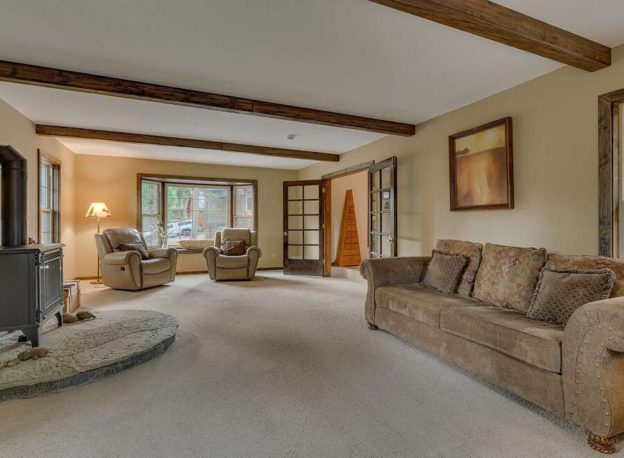 Experience rustic charm in this inviting living room, featuring exposed wooden beams and a cozy fireplace.