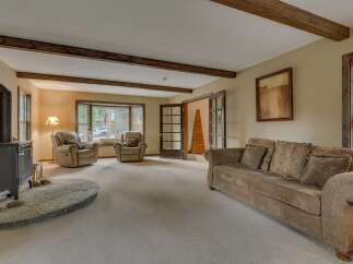 Experience rustic charm in this inviting living room, featuring exposed wooden beams and a cozy fireplace.