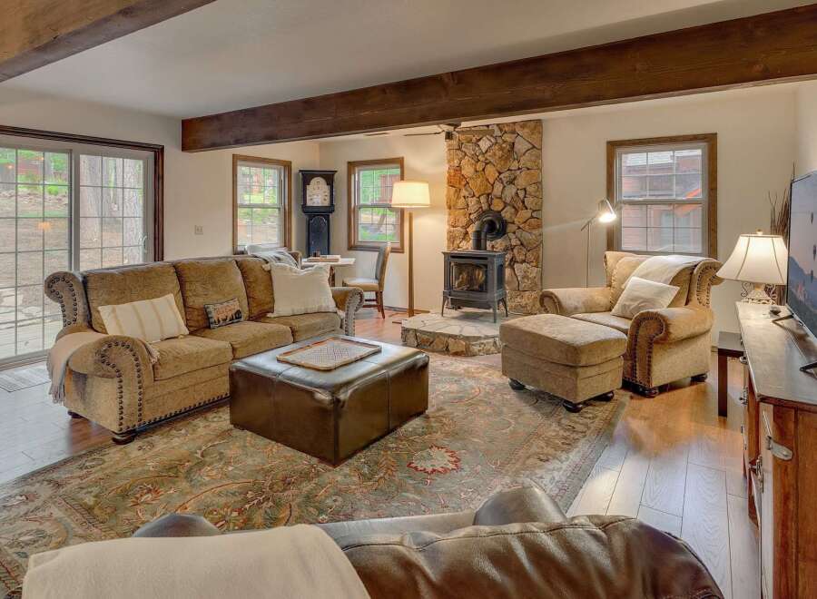 Experience cozy living in this inviting living room, featuring a prominent stone fireplace with a wood-burning stove, perfect for chilly evenings.