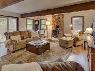 Experience cozy living in this inviting living room, featuring a prominent stone fireplace with a wood-burning stove, perfect for chilly evenings.