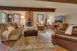 Cozy living room featuring a stone fireplace with a wood-burning stove, comfortable seating including a plush sofa and armchair, and a large area rug.