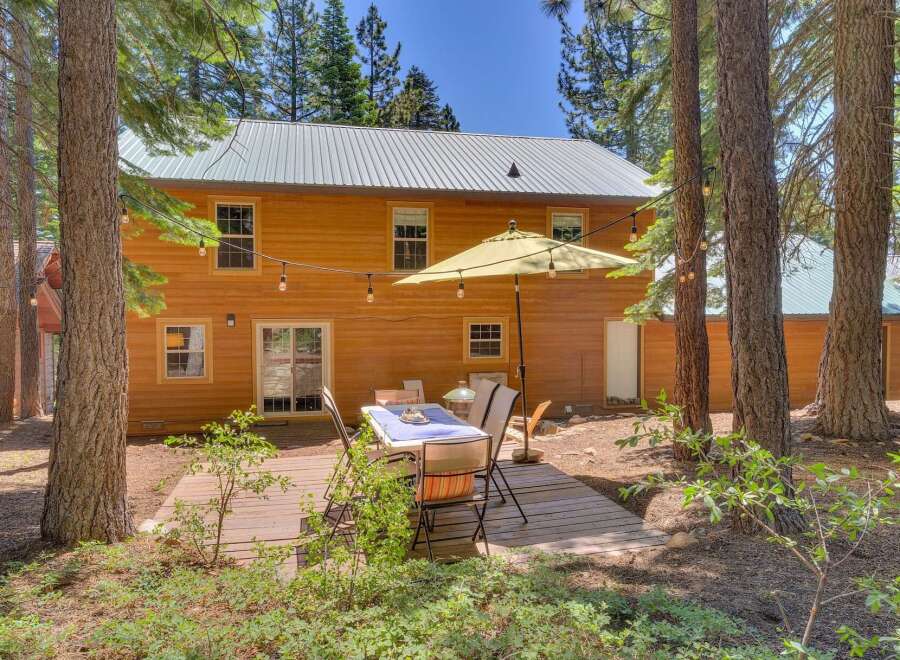 Enjoy outdoor dining and relaxation in this charming backyard oasis, complete with a wooden deck and a picnic table set under a large umbrella.