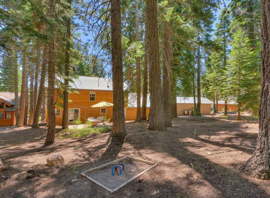 Nestled among tall pine trees, this charming property offers a serene retreat with ample outdoor space.