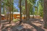 Nestled among tall pine trees, this charming property offers a serene retreat with ample outdoor space.