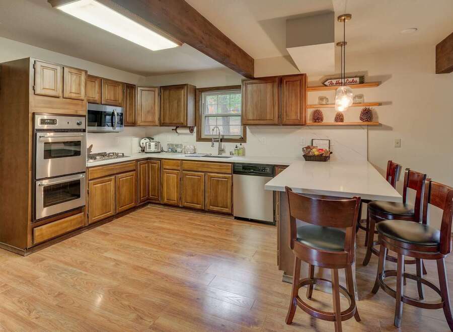 Discover this charming kitchen featuring warm wood cabinetry and sleek stainless steel appliances, including a double oven and microwave.