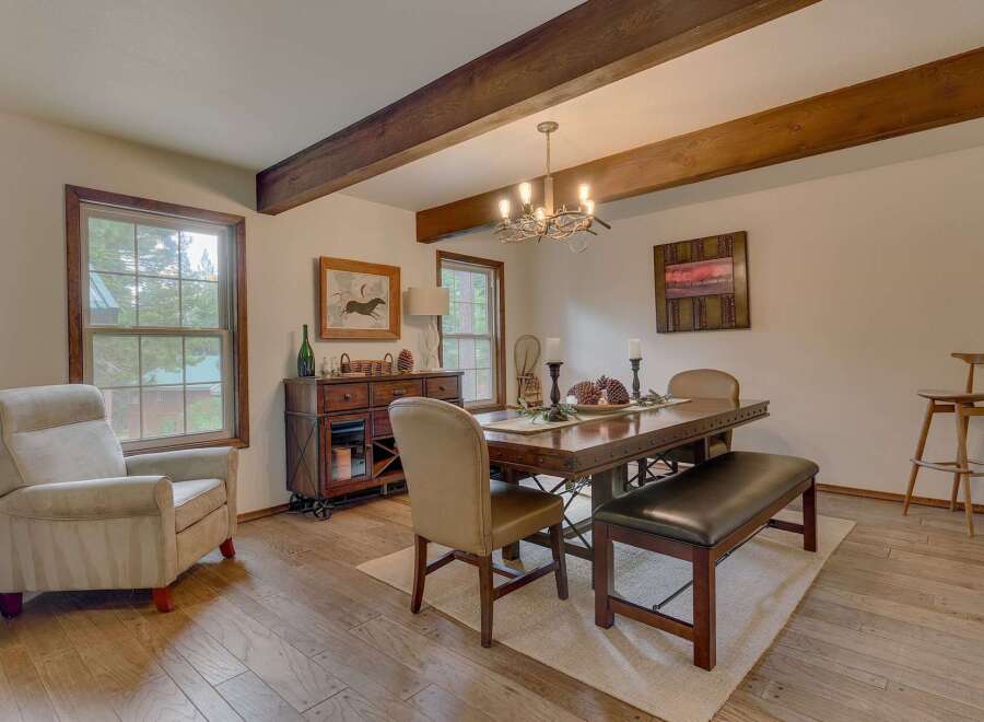 Experience rustic charm in this inviting dining room, featuring exposed wooden beams and a large window overlooking the serene outdoors.