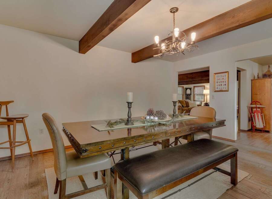 This dining room features a rustic wooden dining table with studded details, complemented by a dark leather bench and upholstered chairs.